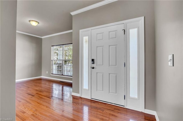 foyer entrance with crown molding, baseboards, and wood finished floors