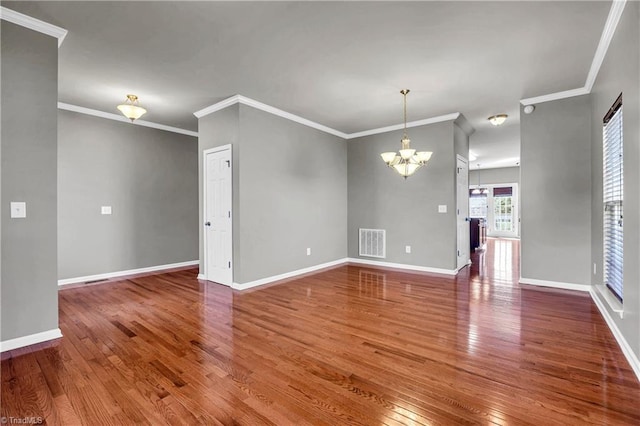 spare room featuring an inviting chandelier, hardwood / wood-style flooring, visible vents, and ornamental molding