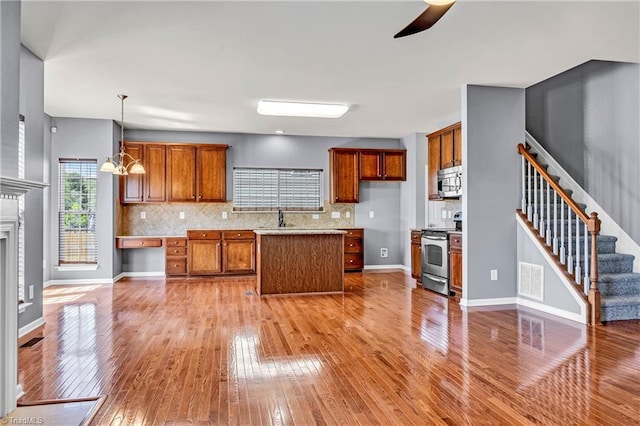 kitchen featuring brown cabinetry, stainless steel appliances, backsplash, and light wood finished floors