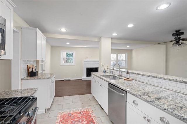 kitchen with sink, plenty of natural light, stainless steel appliances, tasteful backsplash, and white cabinets