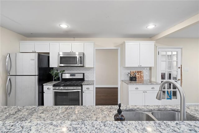 kitchen with white cabinetry, appliances with stainless steel finishes, light stone countertops, and sink