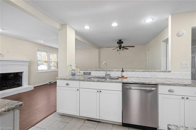 kitchen with light stone countertops, sink, stainless steel dishwasher, and white cabinets