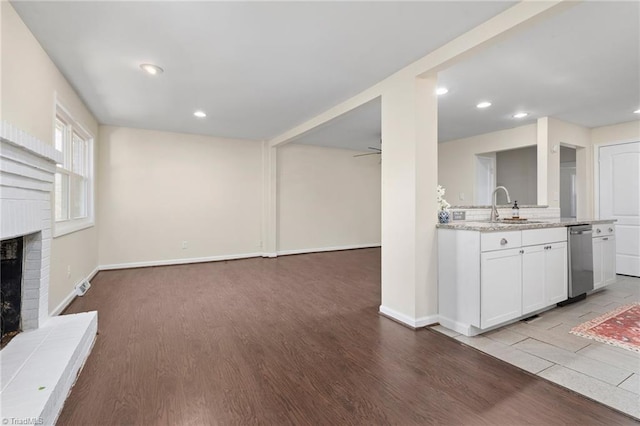 interior space featuring sink, light hardwood / wood-style flooring, white cabinetry, light stone countertops, and a brick fireplace