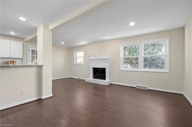 unfurnished living room with dark wood-type flooring and a fireplace