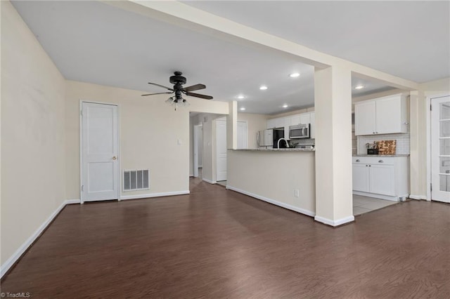 unfurnished living room with dark hardwood / wood-style flooring and ceiling fan