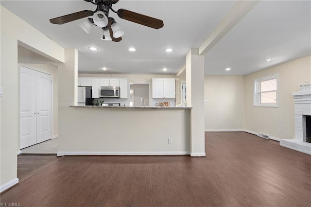 kitchen with light stone counters, white cabinetry, appliances with stainless steel finishes, and kitchen peninsula