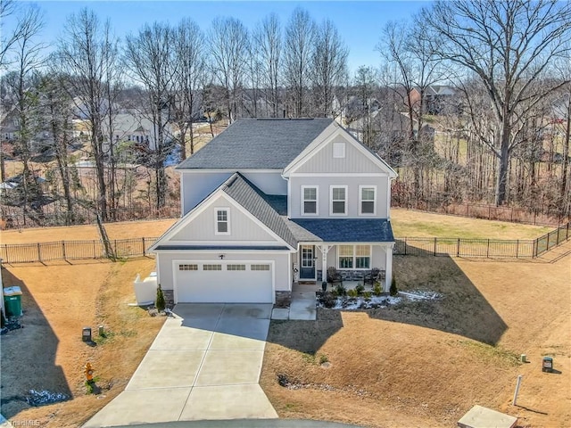 view of front of house featuring a shingled roof, concrete driveway, a front yard, a garage, and fence private yard