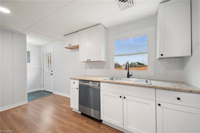 kitchen with light wood finished floors, visible vents, dishwasher, white cabinetry, and a sink