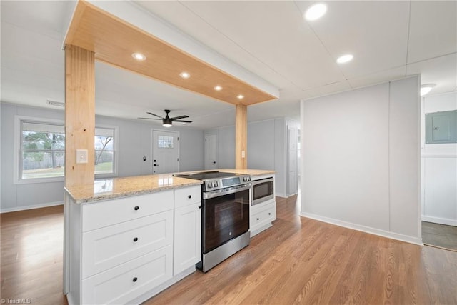 kitchen with light wood-style flooring, stainless steel appliances, white cabinetry, electric panel, and light stone countertops