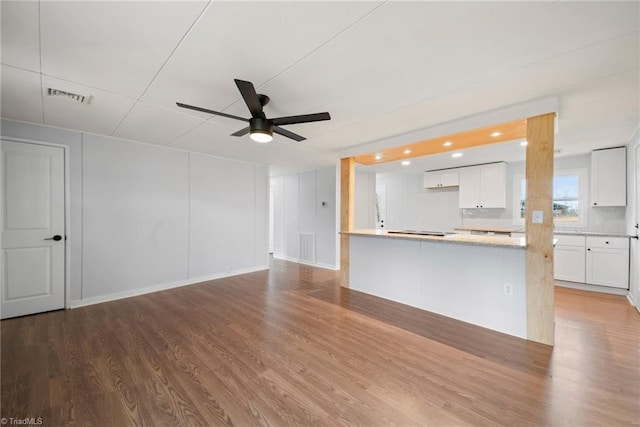 unfurnished living room featuring a ceiling fan, visible vents, and wood finished floors