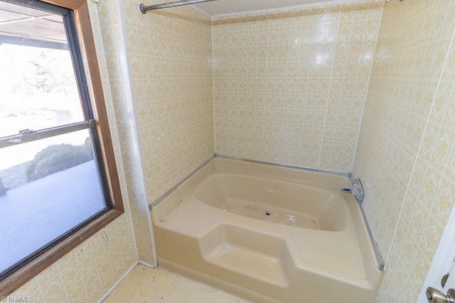 bathroom with a washtub and wallpapered walls