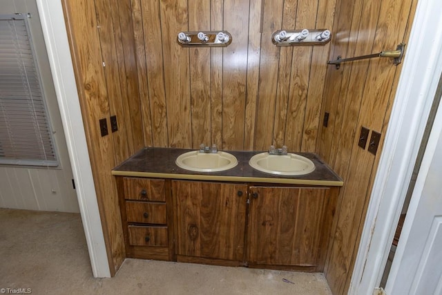 full bath with a sink, wooden walls, and double vanity