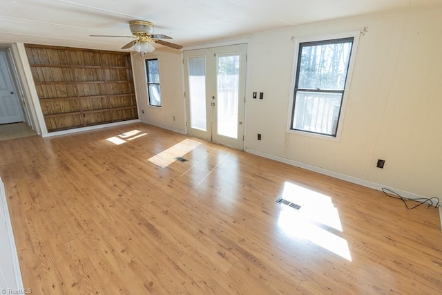 unfurnished living room featuring built in shelves, baseboards, visible vents, light wood finished floors, and ceiling fan