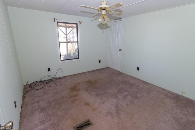 carpeted spare room featuring visible vents and ceiling fan