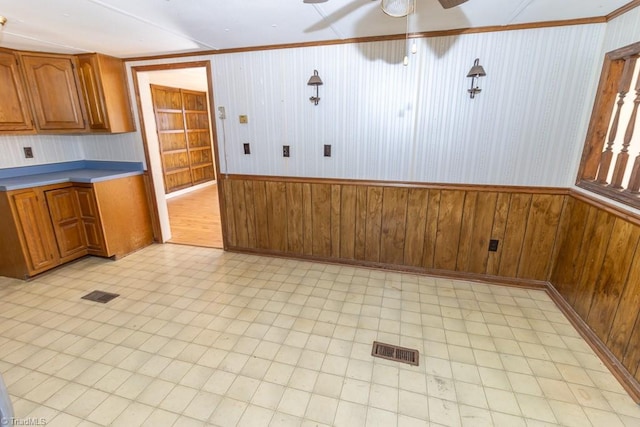 kitchen with visible vents, brown cabinets, wainscoting, and a ceiling fan