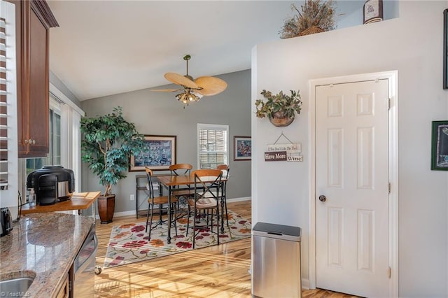 dining area featuring light hardwood / wood-style floors, vaulted ceiling, and ceiling fan