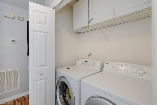 clothes washing area with cabinets, independent washer and dryer, and hardwood / wood-style floors