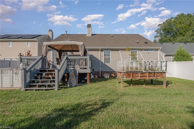 rear view of property featuring a gazebo, a deck, and a lawn