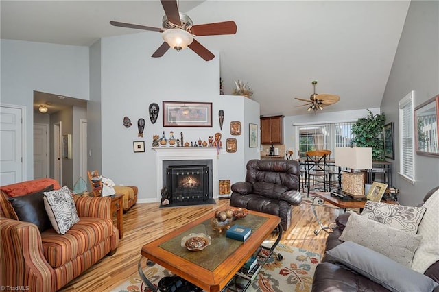 living room featuring ceiling fan, light hardwood / wood-style floors, and high vaulted ceiling