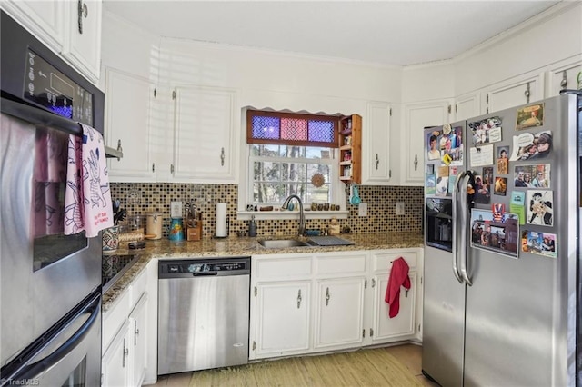 kitchen with sink, appliances with stainless steel finishes, white cabinetry, backsplash, and dark stone countertops