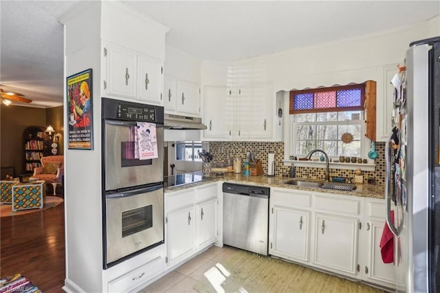 kitchen featuring stainless steel appliances, white cabinetry, light stone countertops, and decorative backsplash