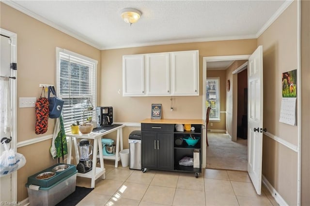 kitchen with white cabinetry, ornamental molding, and light tile patterned floors