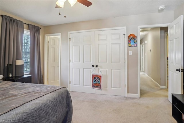 bedroom featuring light colored carpet, ceiling fan, and a closet