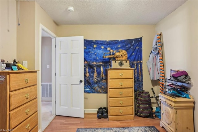 bedroom with a textured ceiling and light wood-type flooring