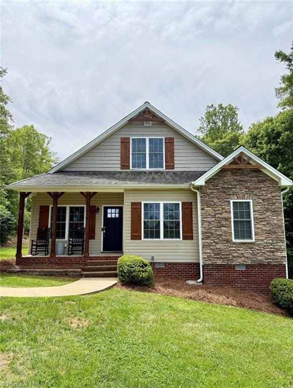 view of front of house featuring a front yard, crawl space, a porch, and stone siding
