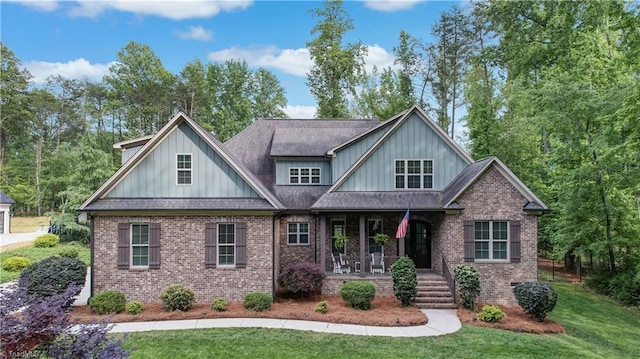 craftsman-style home featuring covered porch, board and batten siding, a front yard, and brick siding