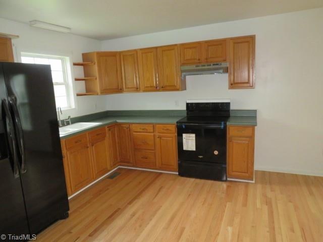 kitchen featuring black appliances, sink, and light wood-type flooring