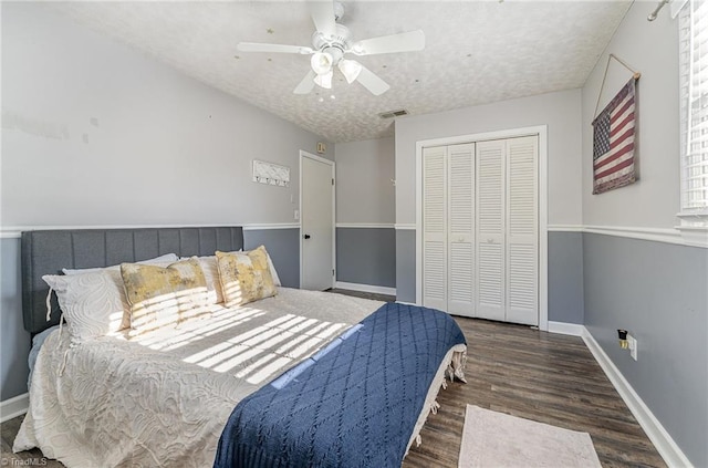 bedroom with a textured ceiling, a closet, visible vents, wood finished floors, and baseboards