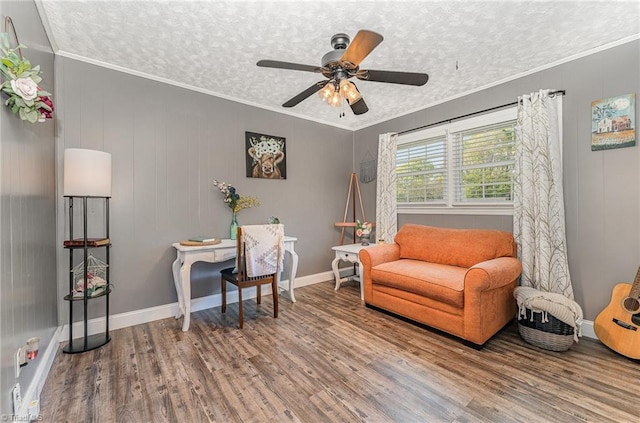sitting room featuring baseboards, ornamental molding, a ceiling fan, a textured ceiling, and wood finished floors