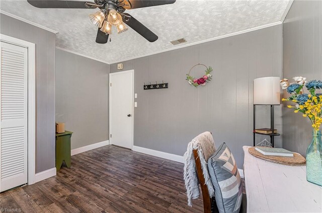 interior space featuring ceiling fan, a textured ceiling, ornamental molding, visible vents, and wood finished floors