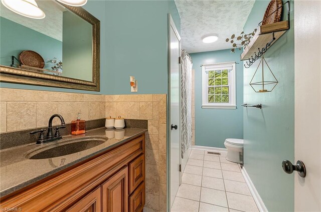 bathroom featuring vanity, tile patterned flooring, a textured ceiling, toilet, and visible vents