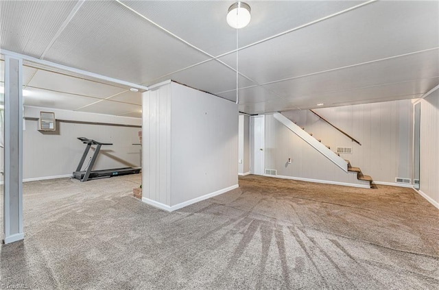 finished basement with stairs, visible vents, and carpet floors