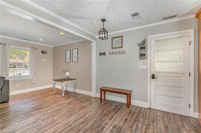 foyer entrance with a textured ceiling, wood finished floors, baseboards, and ornamental molding