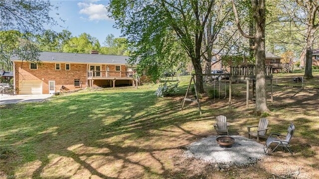 view of yard featuring an outdoor fire pit, a wooden deck, a patio, and a garage