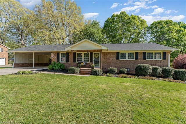 ranch-style home featuring concrete driveway, a front yard, an attached carport, and brick siding