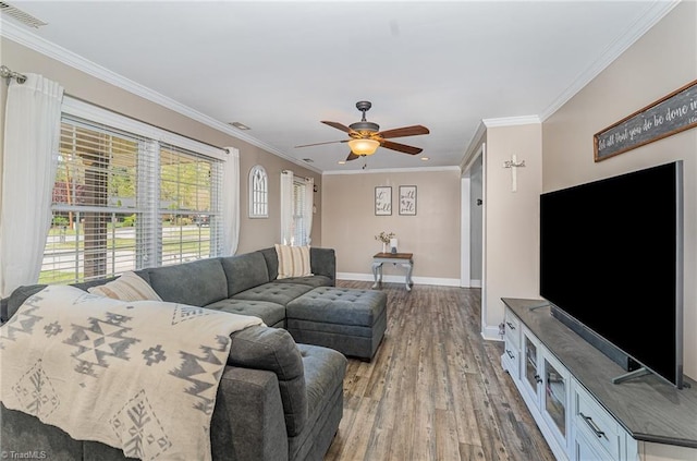 living room featuring baseboards, ornamental molding, visible vents, ceiling fan, and wood finished floors