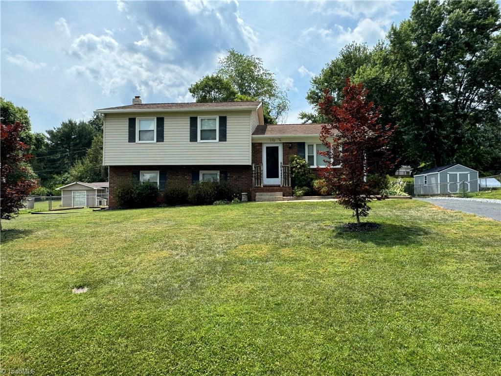 tri-level home featuring a front lawn and a storage shed