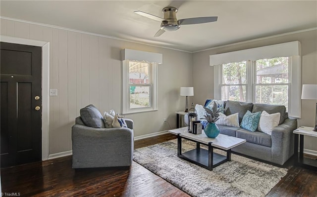 living room with ceiling fan, ornamental molding, wooden walls, and dark wood-type flooring