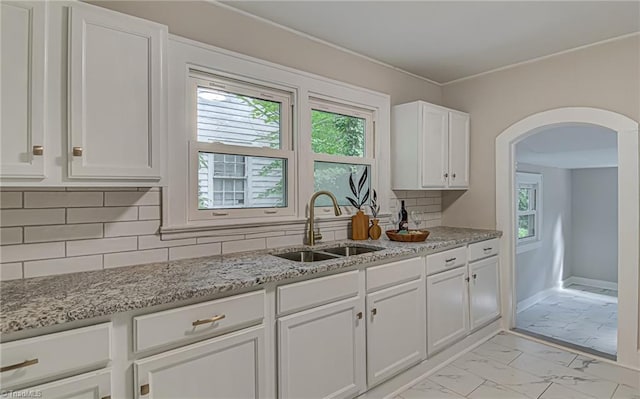 kitchen featuring decorative backsplash, white cabinetry, sink, and light stone countertops