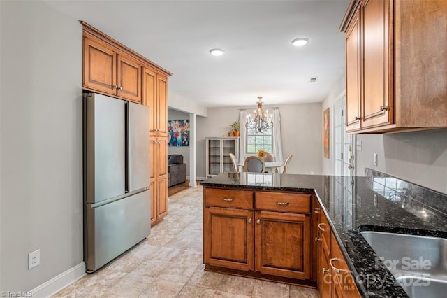 845 Montgomery Ct, Walnut Cove, NC 27052 - kitchen featuring freestanding refrigerator, brown cabinetry, a peninsula, a chandelier, and baseboards
