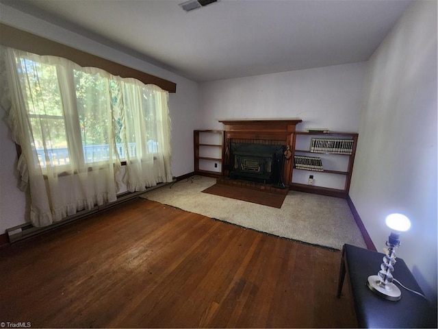 unfurnished living room with a baseboard heating unit and dark wood-type flooring