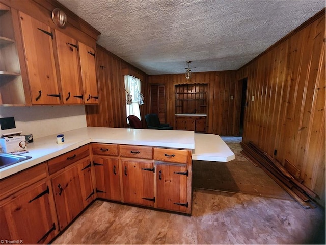 kitchen featuring light hardwood / wood-style flooring, wooden walls, kitchen peninsula, and a textured ceiling