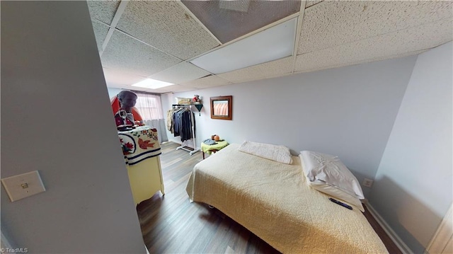 bedroom with a drop ceiling, wood-type flooring, and a closet