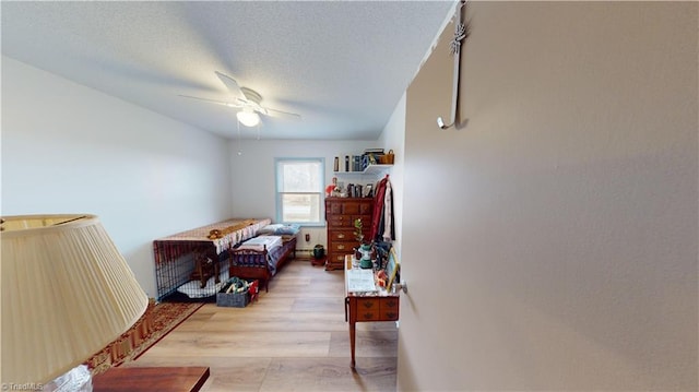 bedroom featuring ceiling fan, light hardwood / wood-style flooring, and a textured ceiling