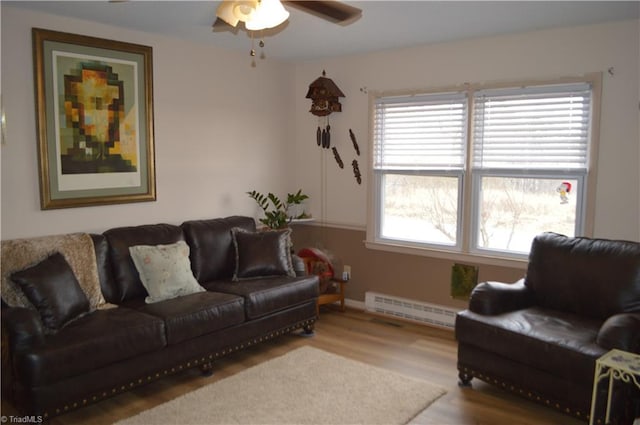 living room with baseboard heating, ceiling fan, plenty of natural light, and wood-type flooring