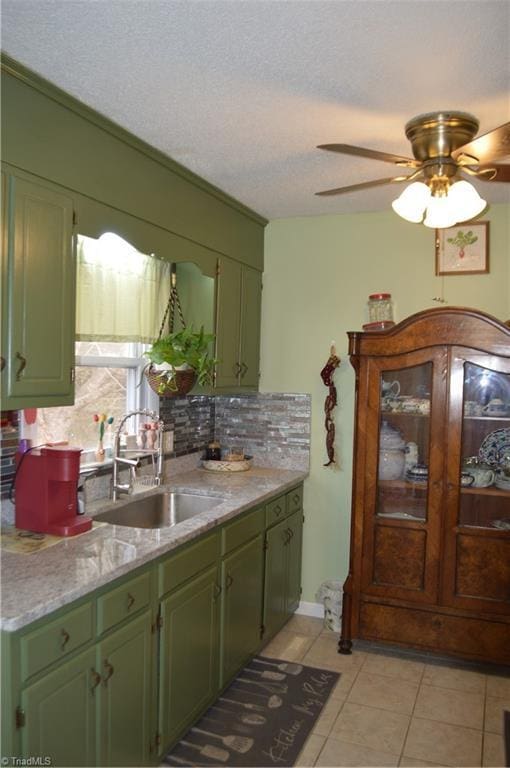 kitchen featuring sink, light tile patterned floors, decorative backsplash, and a textured ceiling